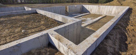 Concrete foundation walls forming a maze-like layout on a dirt construction site.