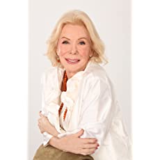 Uma mulher de camisa branca está sentada com os braços cruzados e sorrindo.