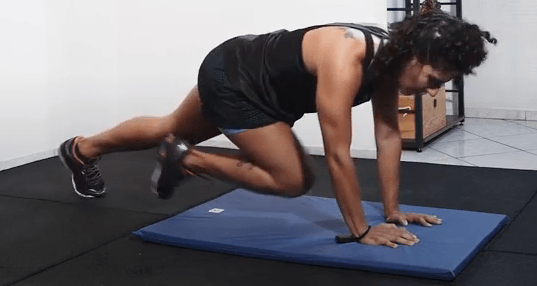 Uma mulher está fazendo flexões em um tapete azul.