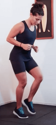 Uma mulher de blusa preta e shorts está pulando no ar.