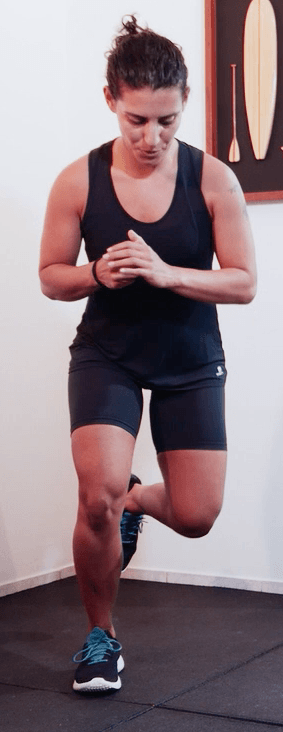 Uma mulher está fazendo um exercício de estocada em uma academia.