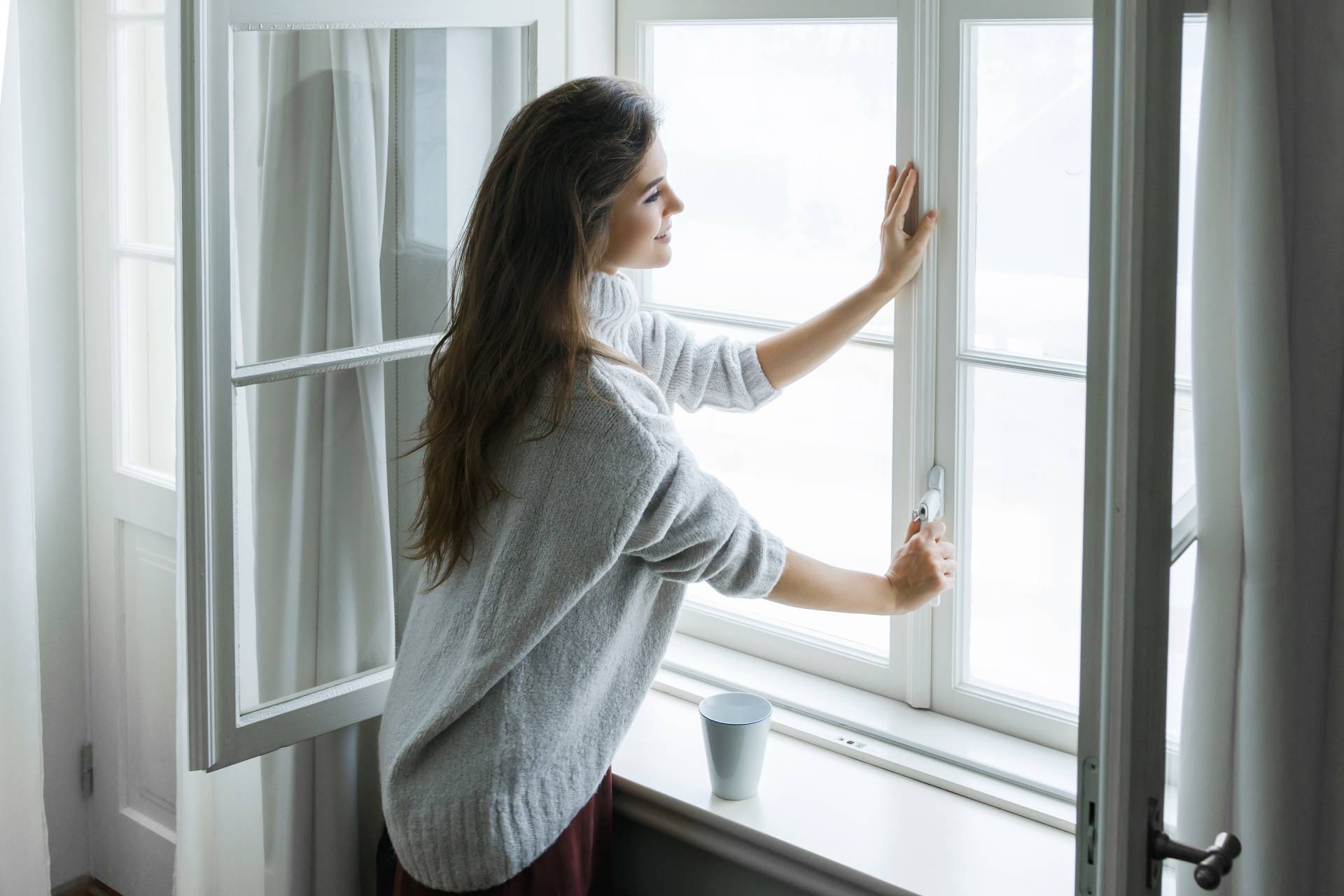donna mentre apre la finestra di casa