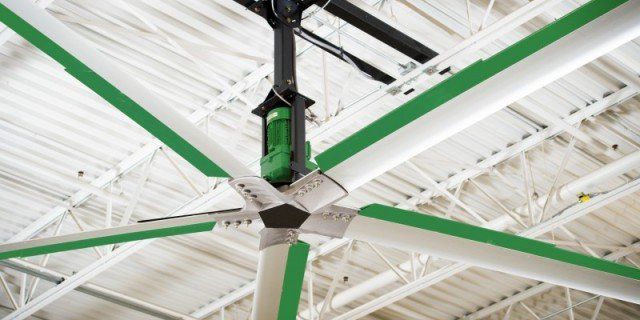 A ceiling fan with green blades is hanging from the ceiling of a building.