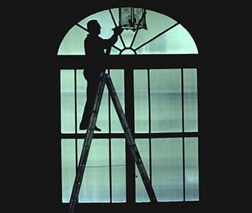 Cleaning — Silhouette of a Man Standing on a Ladder Cleaned Window in Nashville, TN Cleaning — Silhouette of a Man Standing on a Ladder Cleaned Window in Nashville, TN