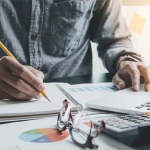 Business Returns — Accountant's hand Holding Pen Making Notes And Using Laptop in Hesperia, CA Business Returns — Accountant's hand Holding Pen Making Notes And Using Laptop in Hesperia, CA