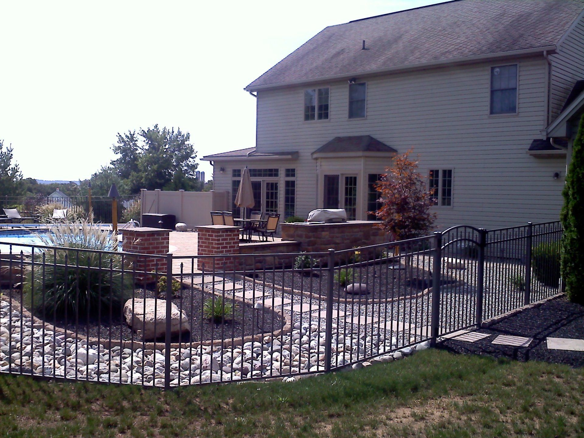 Backyard patio with a fence, pool, and a two-story beige house in Lancaster, PA.