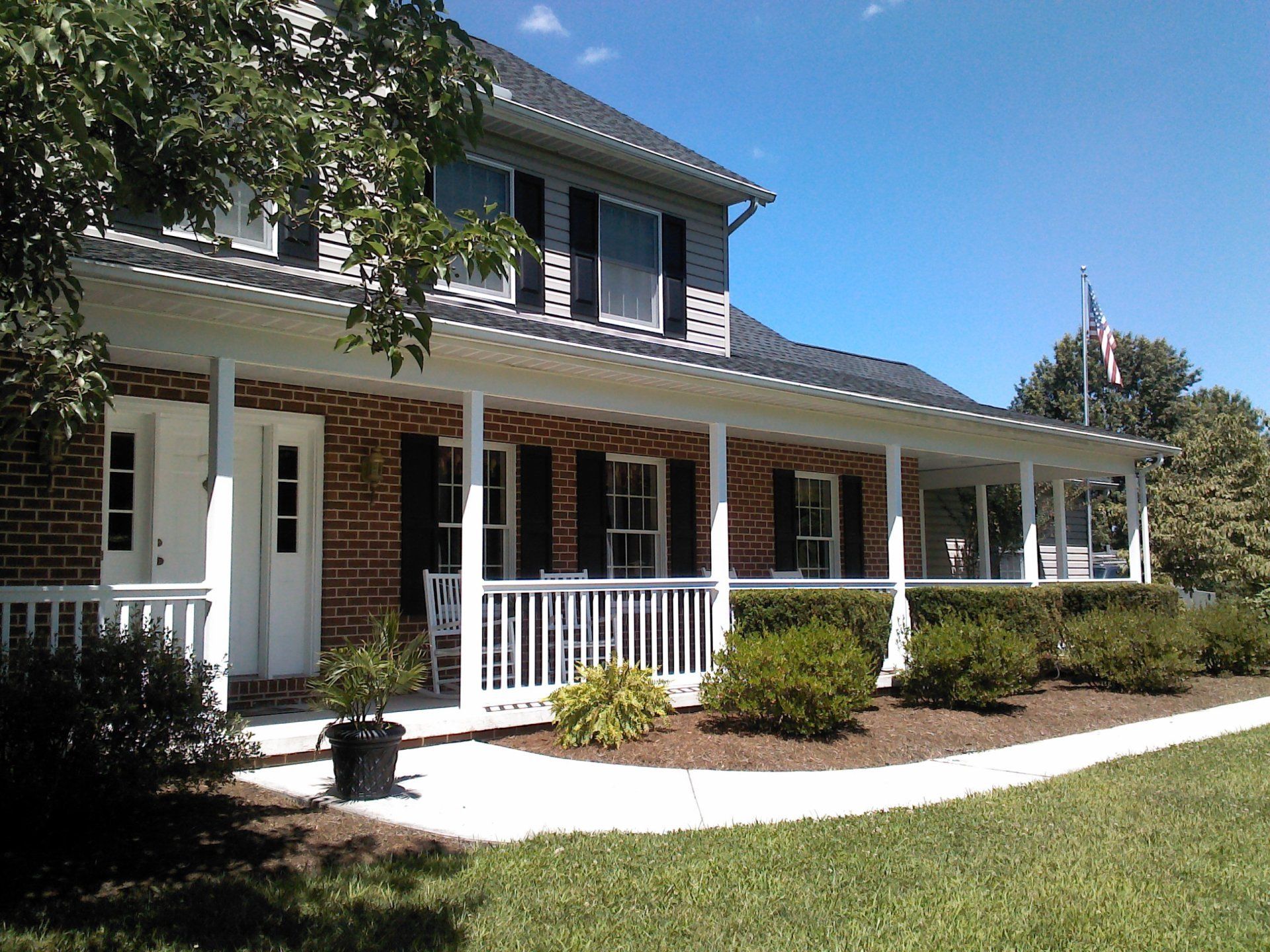 Two-story brick house with a wraparound porch by Millcreek Fence & Decks in Lancaster, PA.