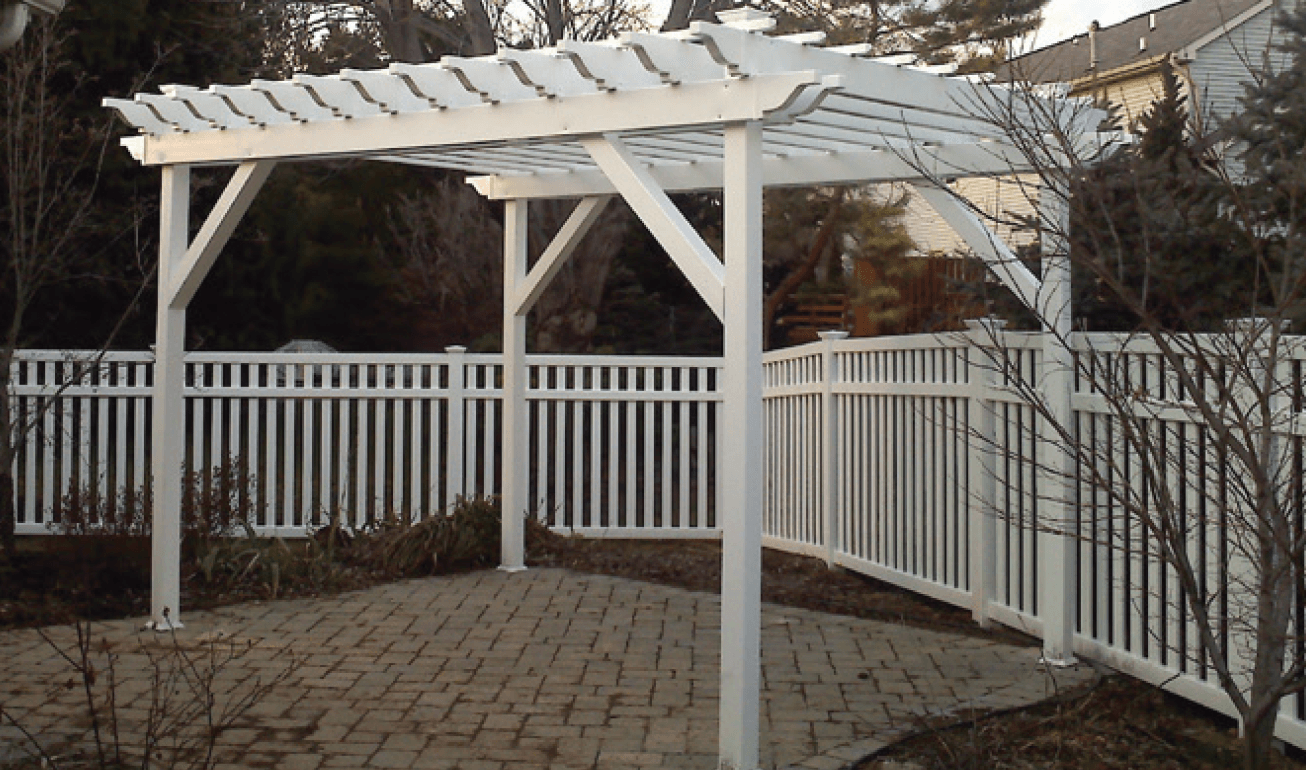 White pergola over a brick patio, surrounded by a white picket fence.