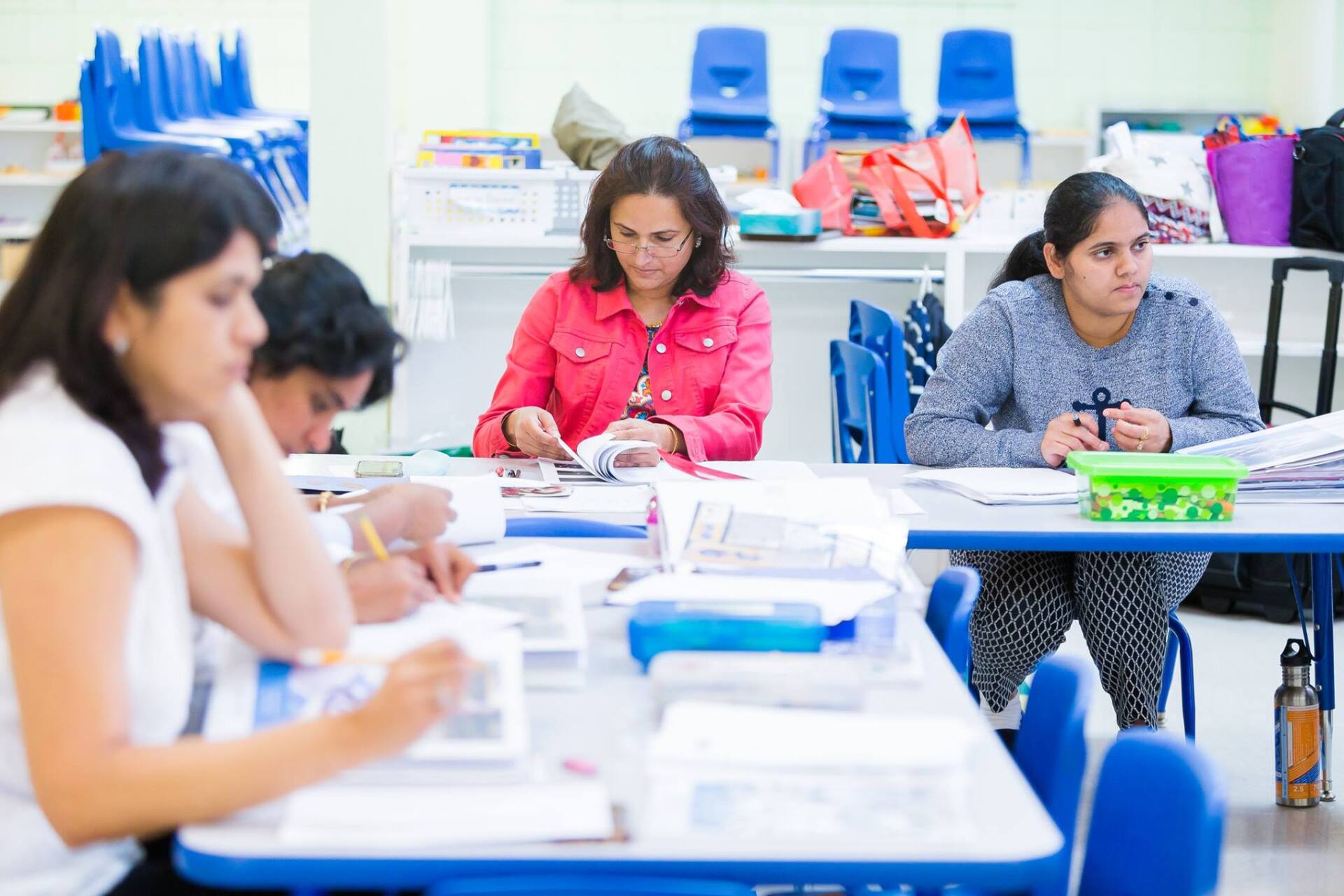 A group of women are sitting at tables in a classroom.
