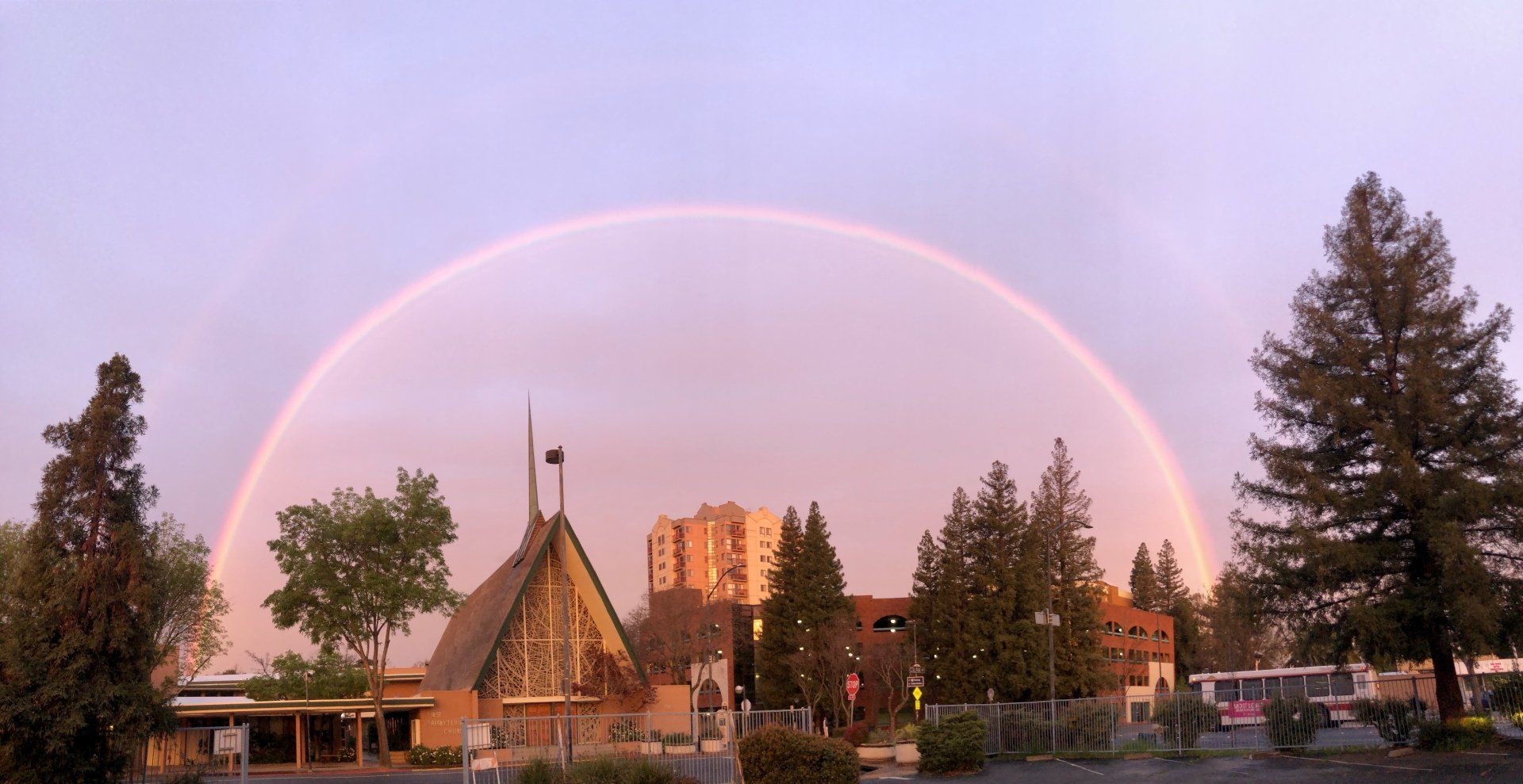 There is a rainbow in the sky over a church.