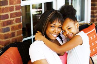 Mother & Daughter In Front of House