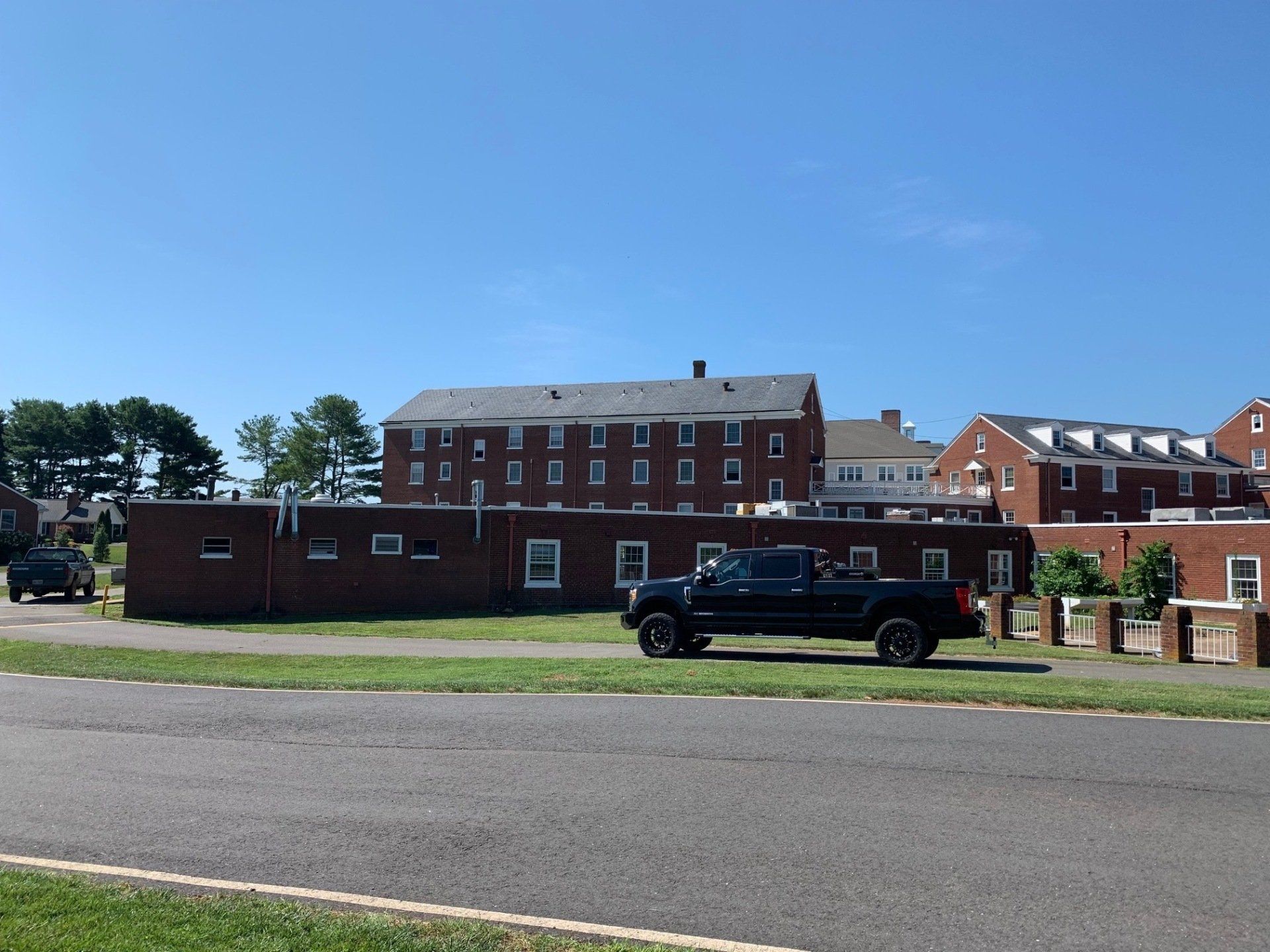 Black SUV parked in front of a red brick building under a clear blue sky.