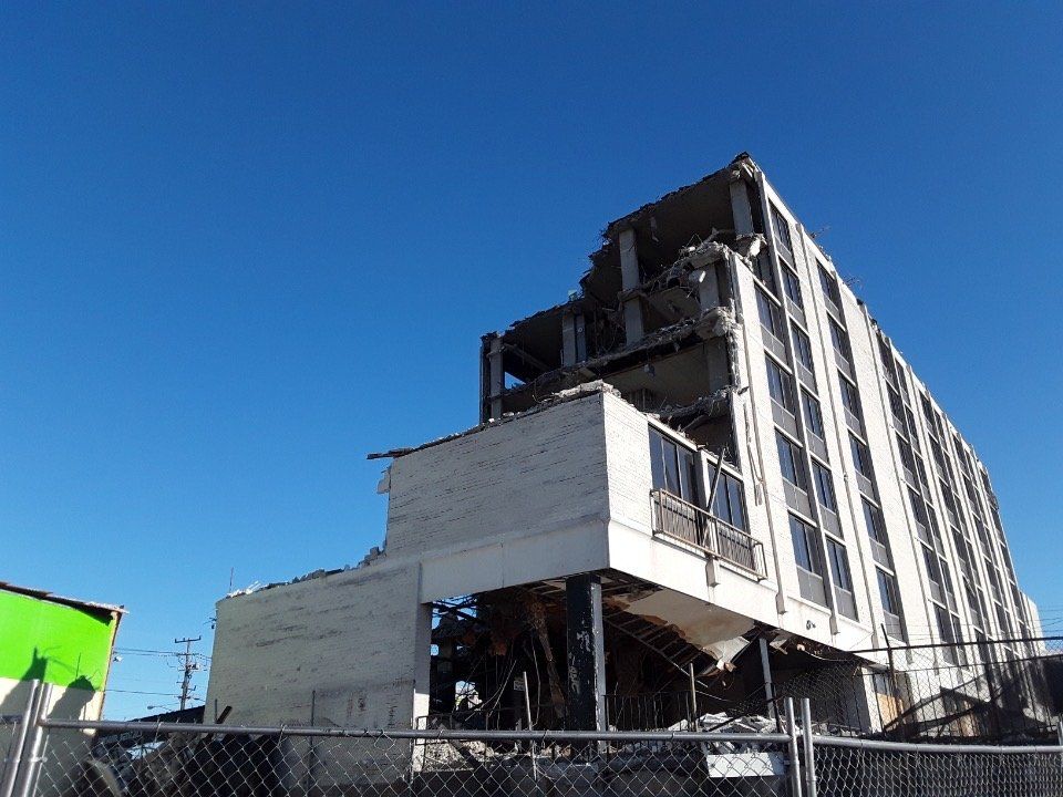 Damaged multi-story building with exposed structure under a clear blue sky