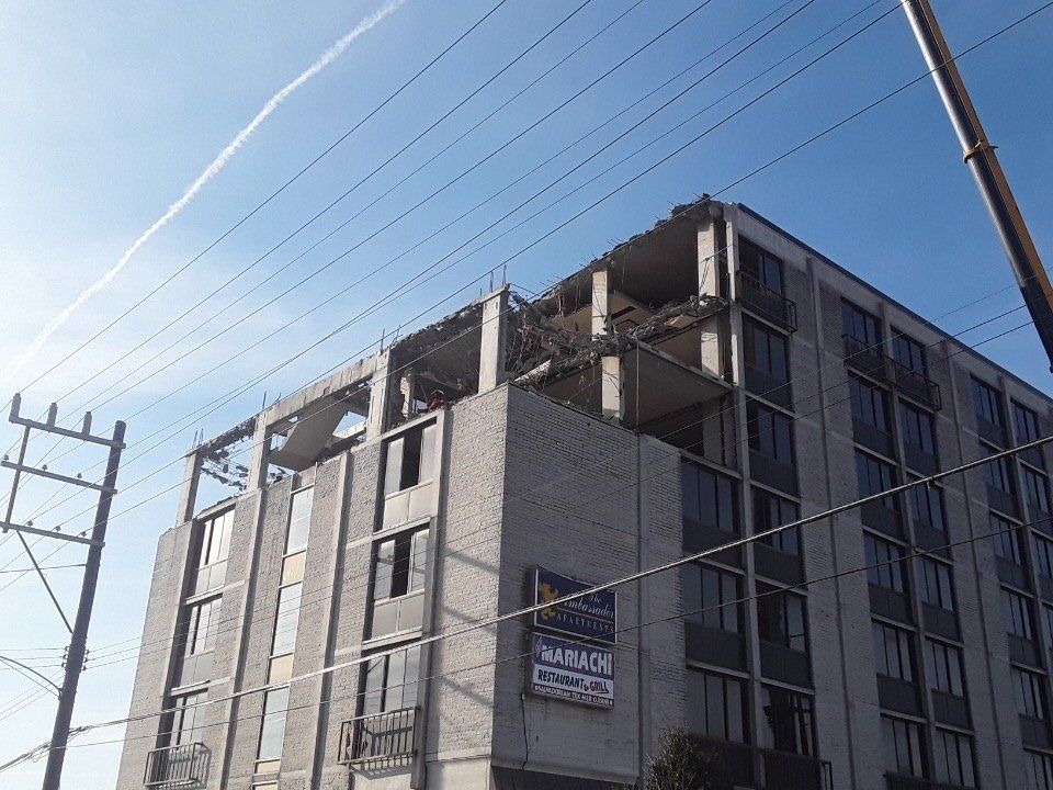 Partially built concrete building beside power lines under a clear blue sky