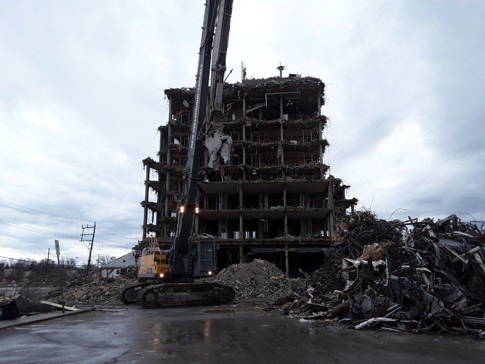 Collapsed building with rubble and a crane at a disaster site under a cloudy sky