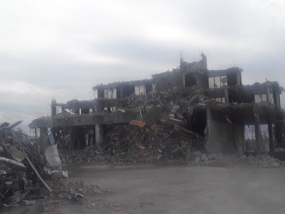 Collapsed, damaged building rubble under a gray sky after destruction