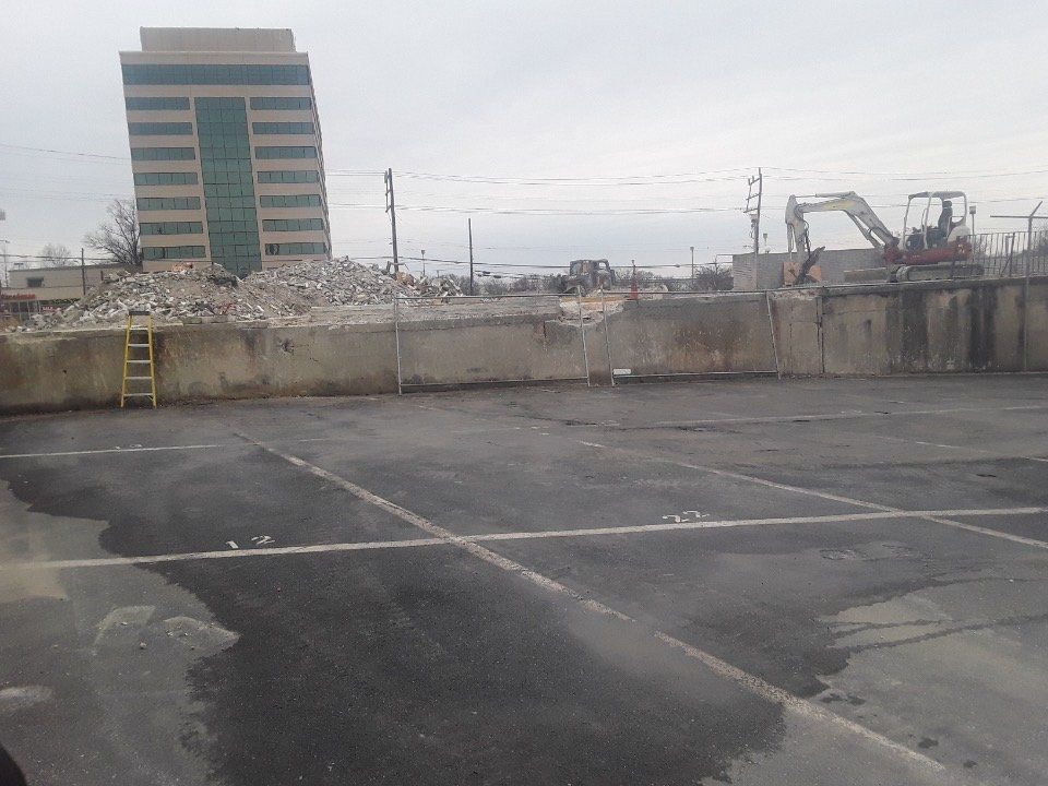Empty rooftop parking lot with a tall building and construction equipment in the distance