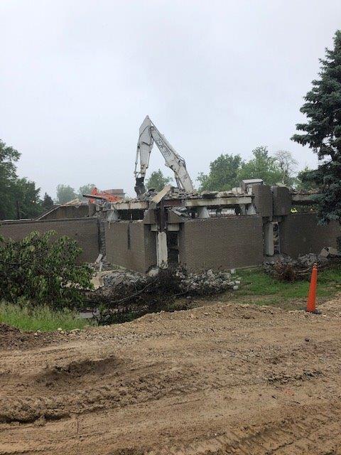 Demolition excavator tearing down a building with rubble and dirt in the foreground