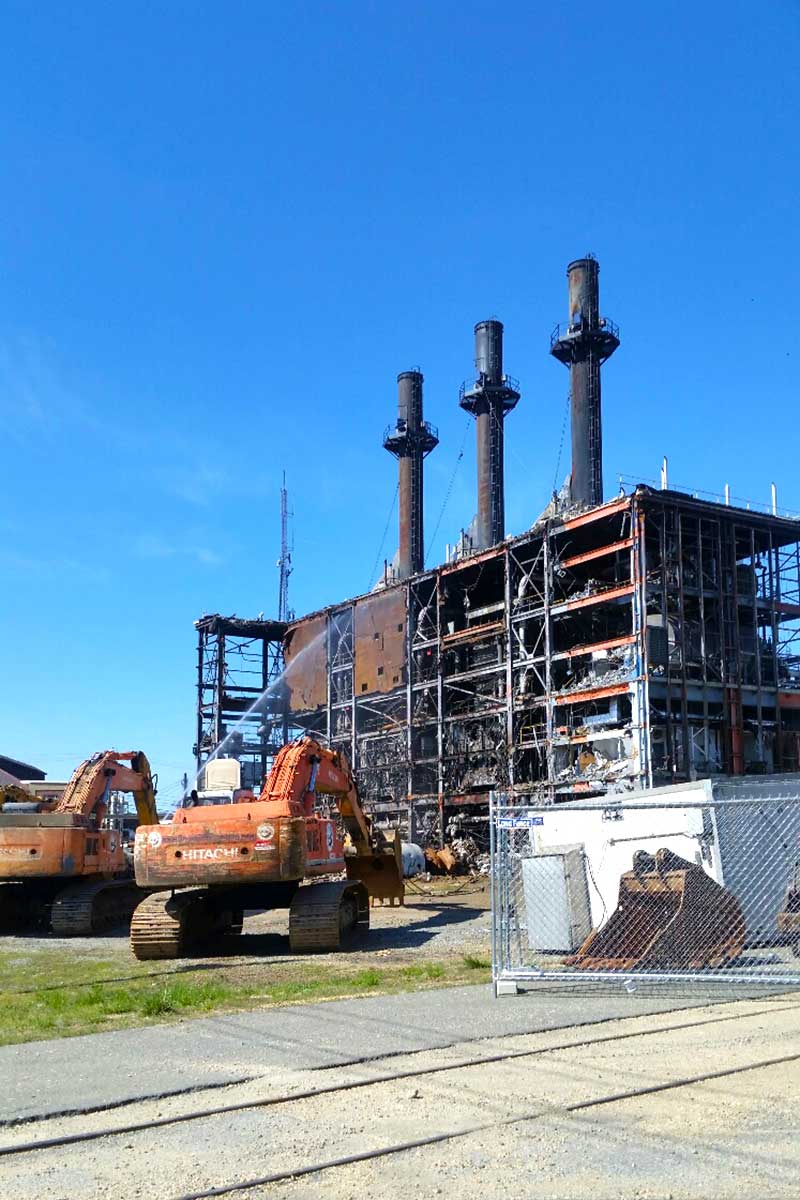 Construction site with heavy equipment and a steel building frame against a clear blue sky