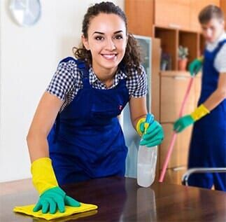 Woman Smiles While Wiping a Table — Janitorial Service in Atlanta, GA Woman Smiles While Wiping a Table — Janitorial Service in Atlanta, GA