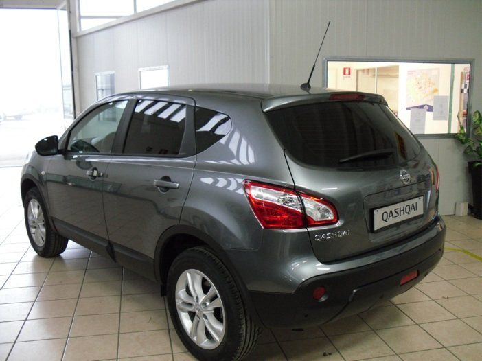 SUV Nissan Qashqai grigio parcheggiato all'interno. Vista posteriore con vetri oscurati e stemma