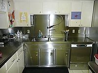 Modern stainless-steel kitchen with sink, cabinets, and dishwasher under white upper cabinets