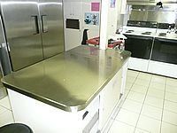 Modern kitchen with stainless steel island, double fridge, and black-and-white cabinets