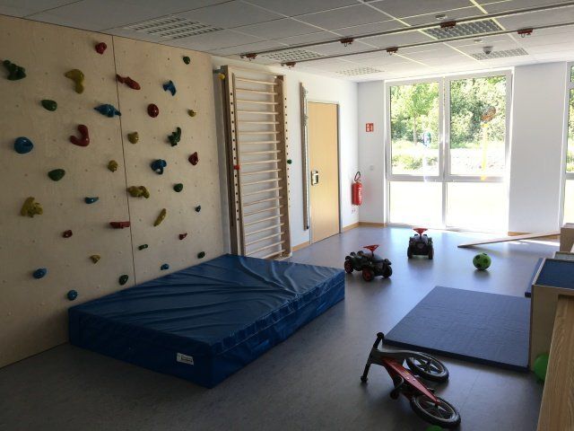 Ein Raum mit einer Kletterwand und einer blauen Matte