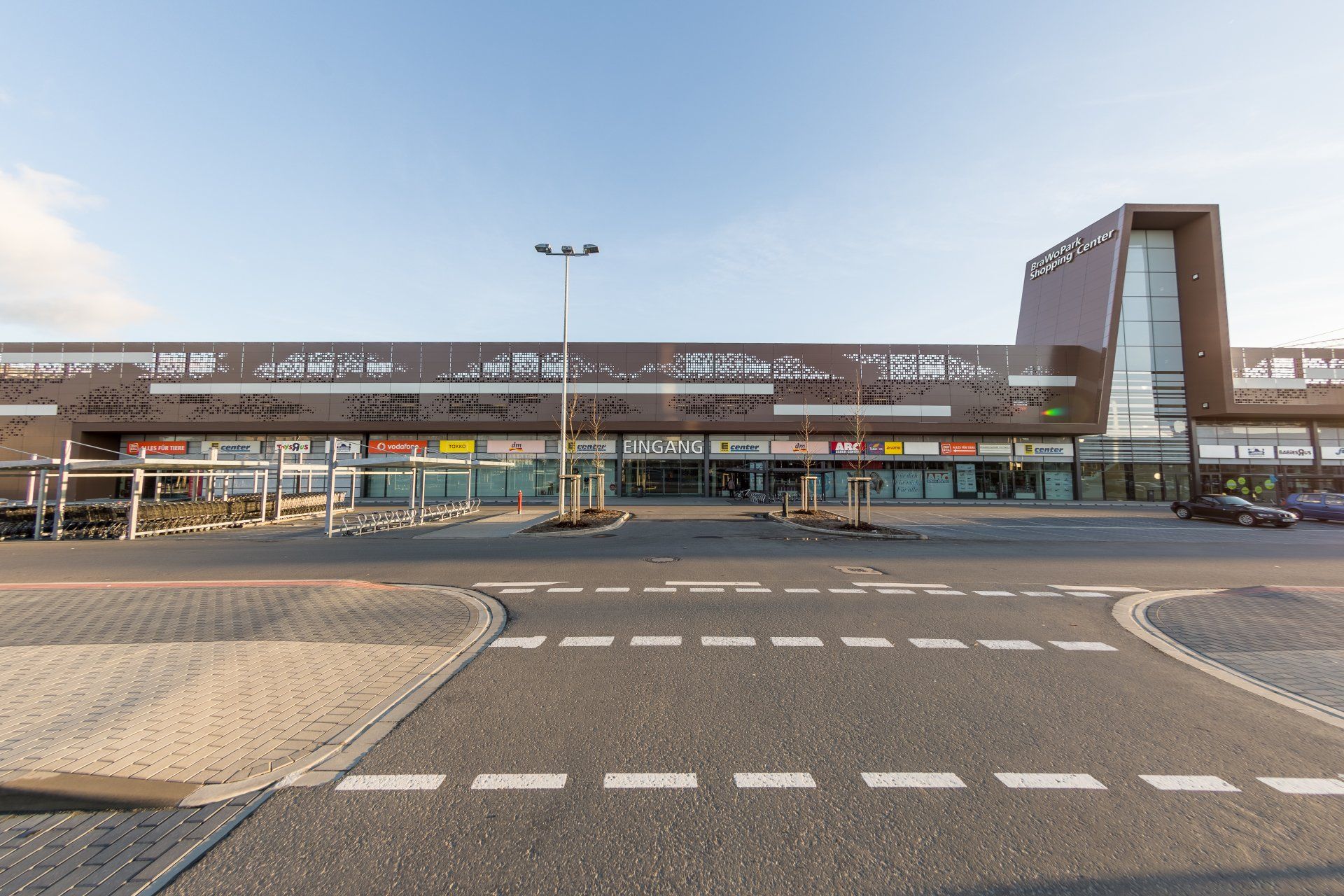 Neben einer Straße steht ein großes Gebäude mit vielen Fenstern.