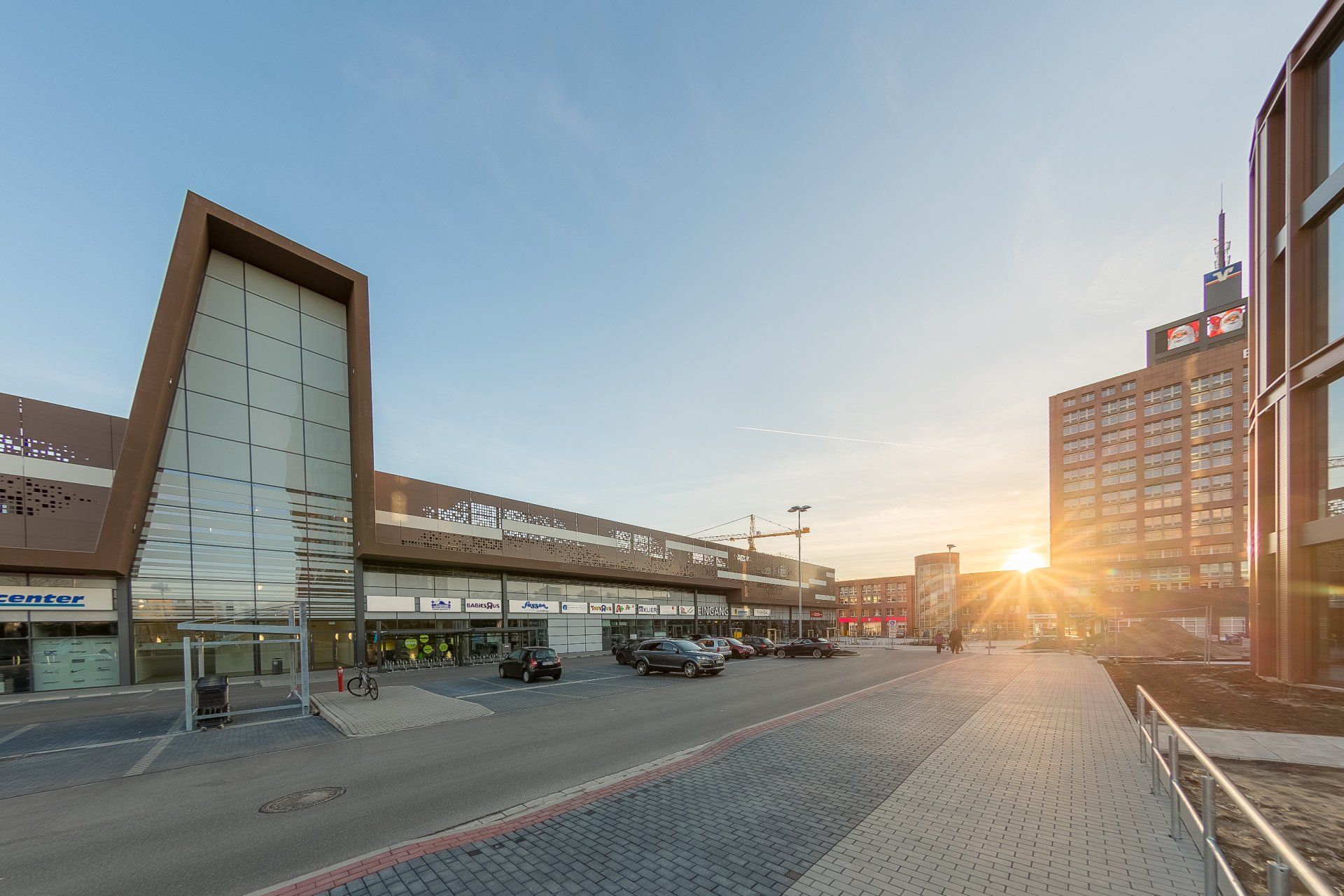 Ein großes Gebäude mit vielen Fenstern und davor geparkten Autos.
