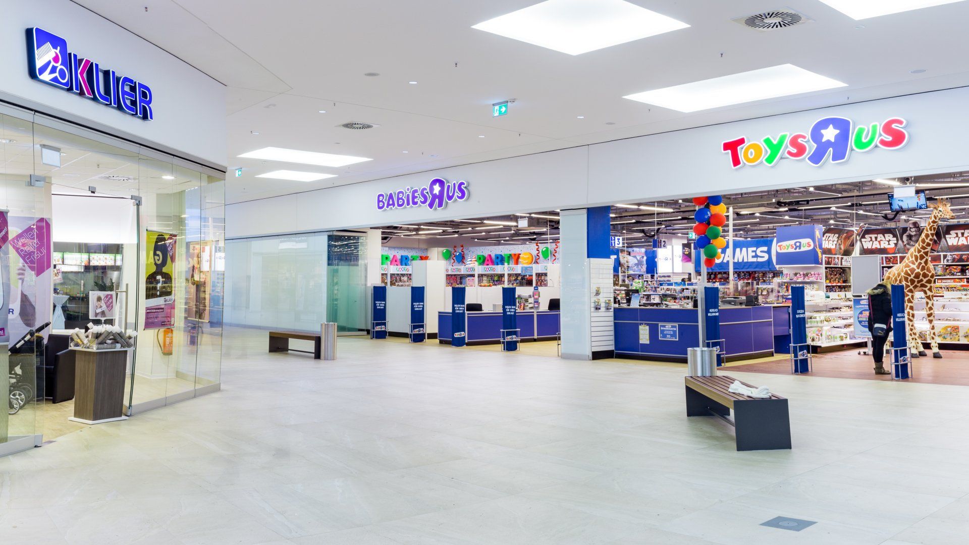 Ein Toys R Us-Laden in einem Einkaufszentrum mit einer Bank davor.
