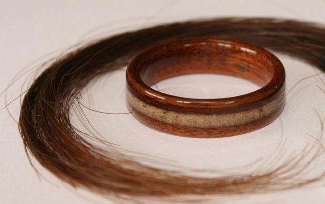 A wooden memorial ring with an inlay of horse hair and ashes. A lock of horse hair encircles the ring.