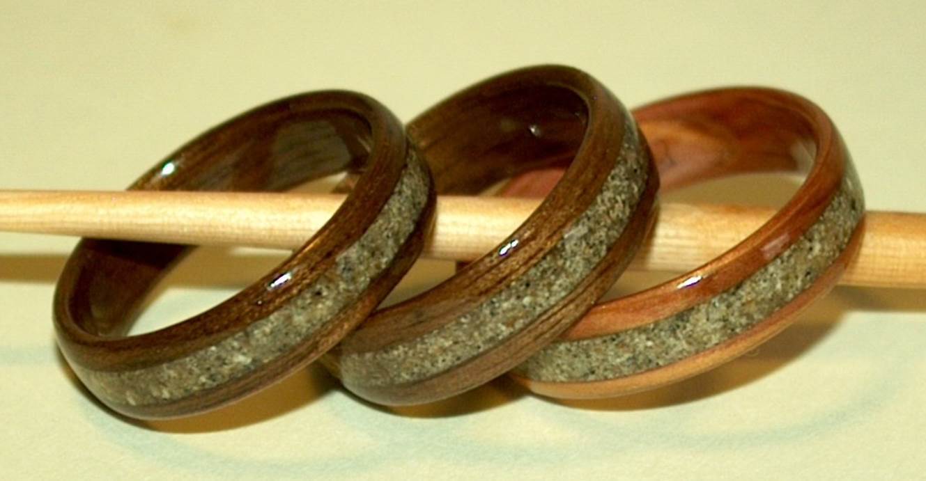 Three wooden memorial rings resting on a wooden stick. The rings are inlaid with ashes.