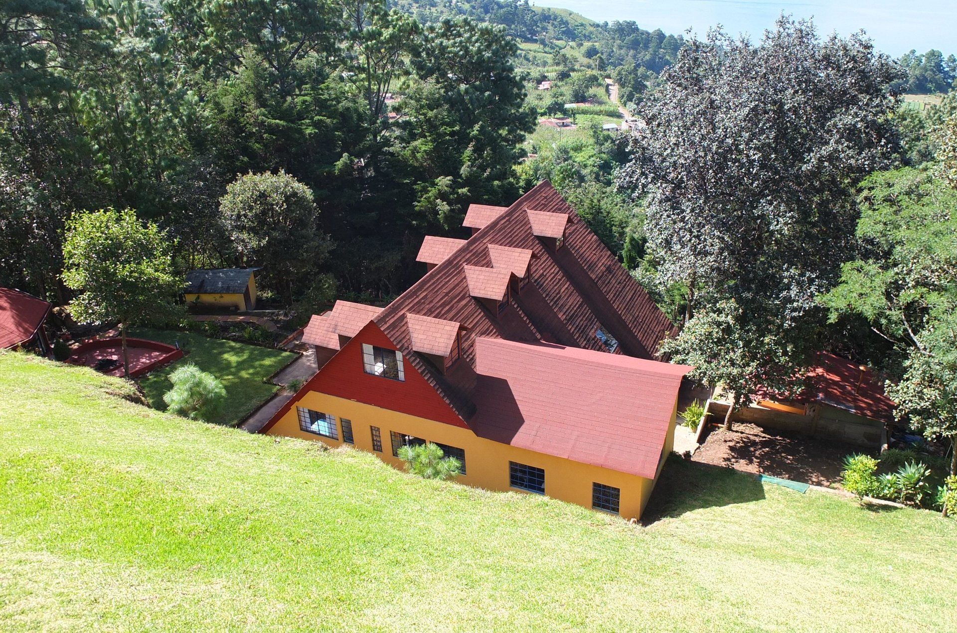 Ein Haus mit rotem Dach steht auf einem grasbewachsenen Hügel