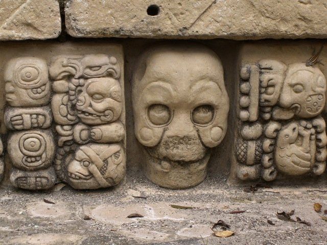 Drei Totenköpfe sind in eine Steinmauer gehauen.