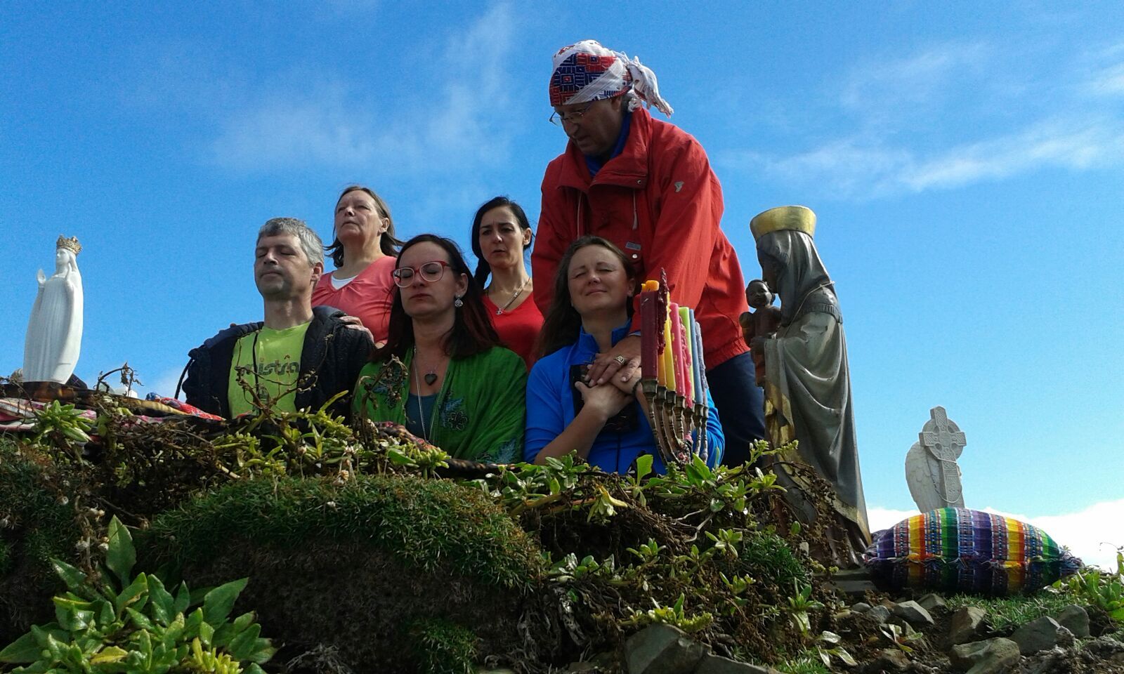 Eine Gruppe von Menschen steht auf einem Hügel, im Hintergrund sind Statuen zu sehen.