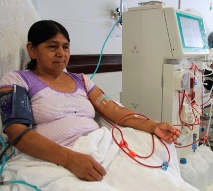 Eine Frau sitzt in einem Krankenhausbett und bekommt eine Dialysebehandlung