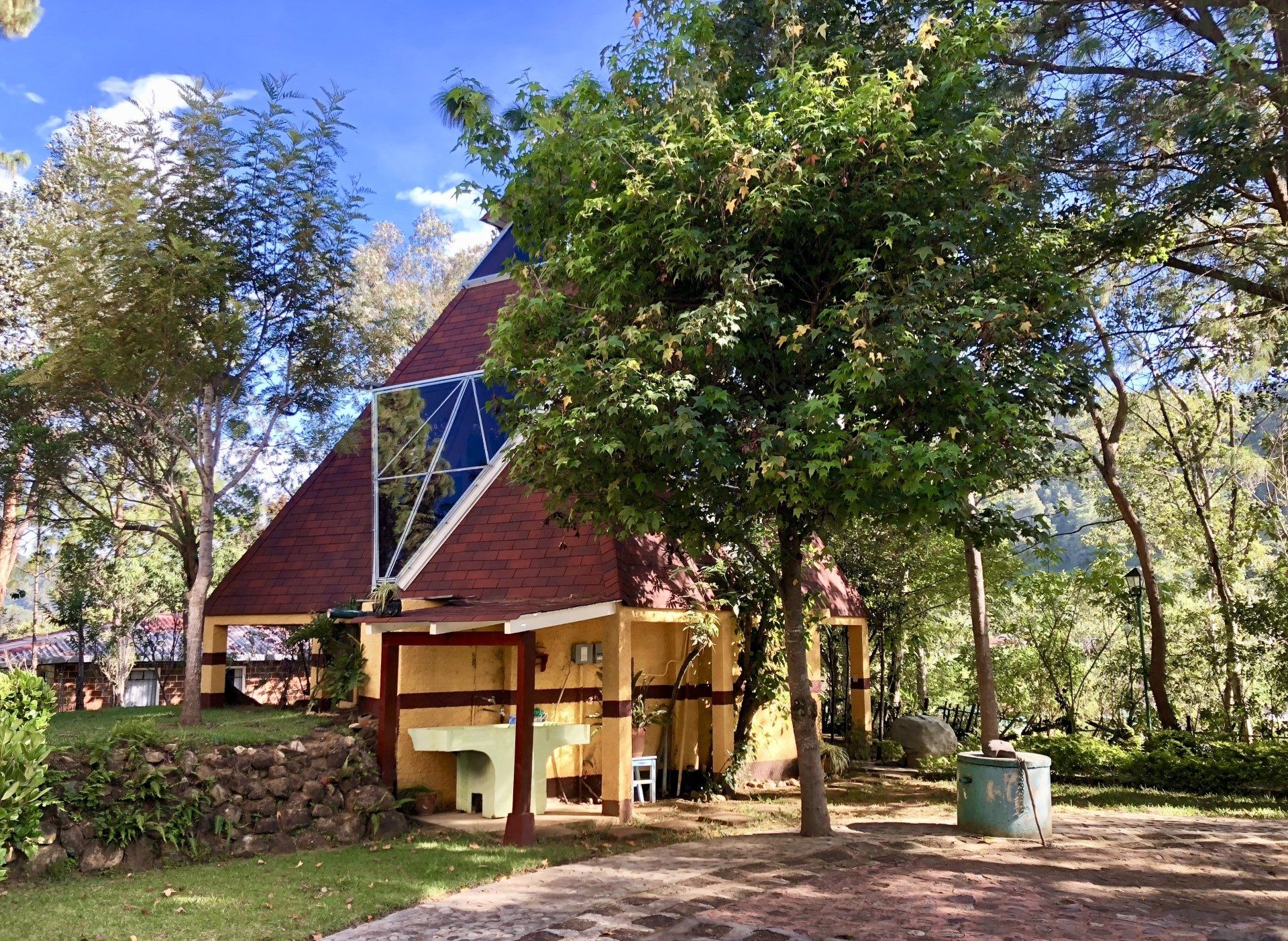 Ein kleines Haus mit rotem Dach ist von Bäumen umgeben.
