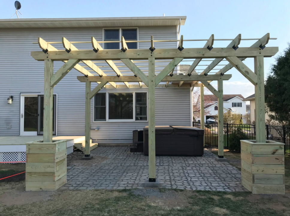 Backyard patio with wooden pergola, paver floor, and outdoor seating beside a house