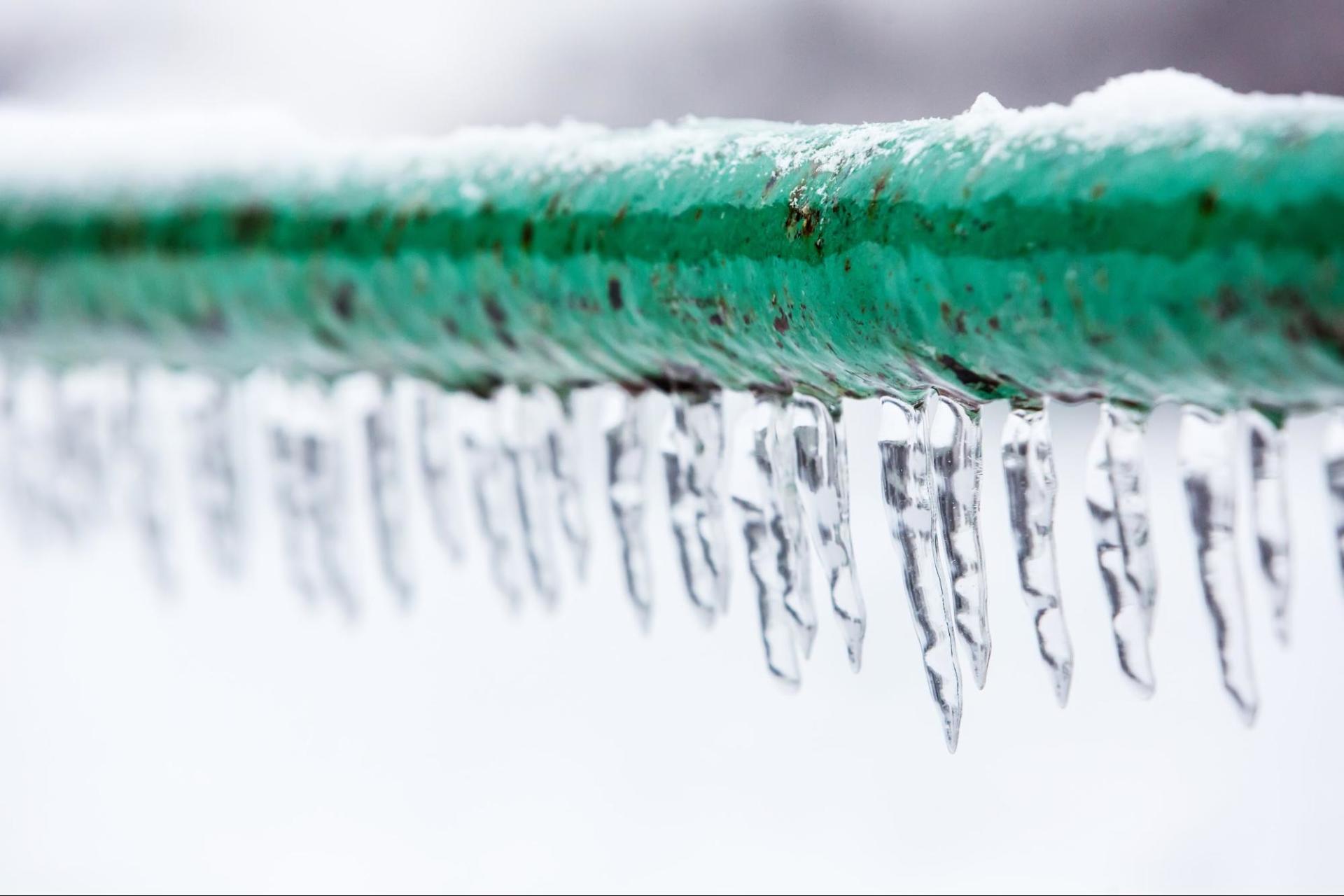 Icicles dangle off a frozen green pipe outside - Restoration 1 of Tuscaloosa