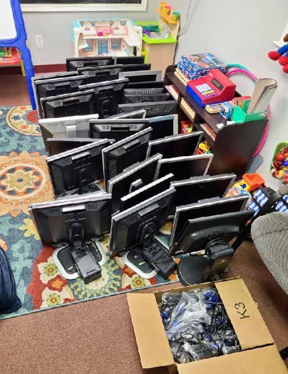 A bunch of computer monitors are stacked on top of each other in a room.