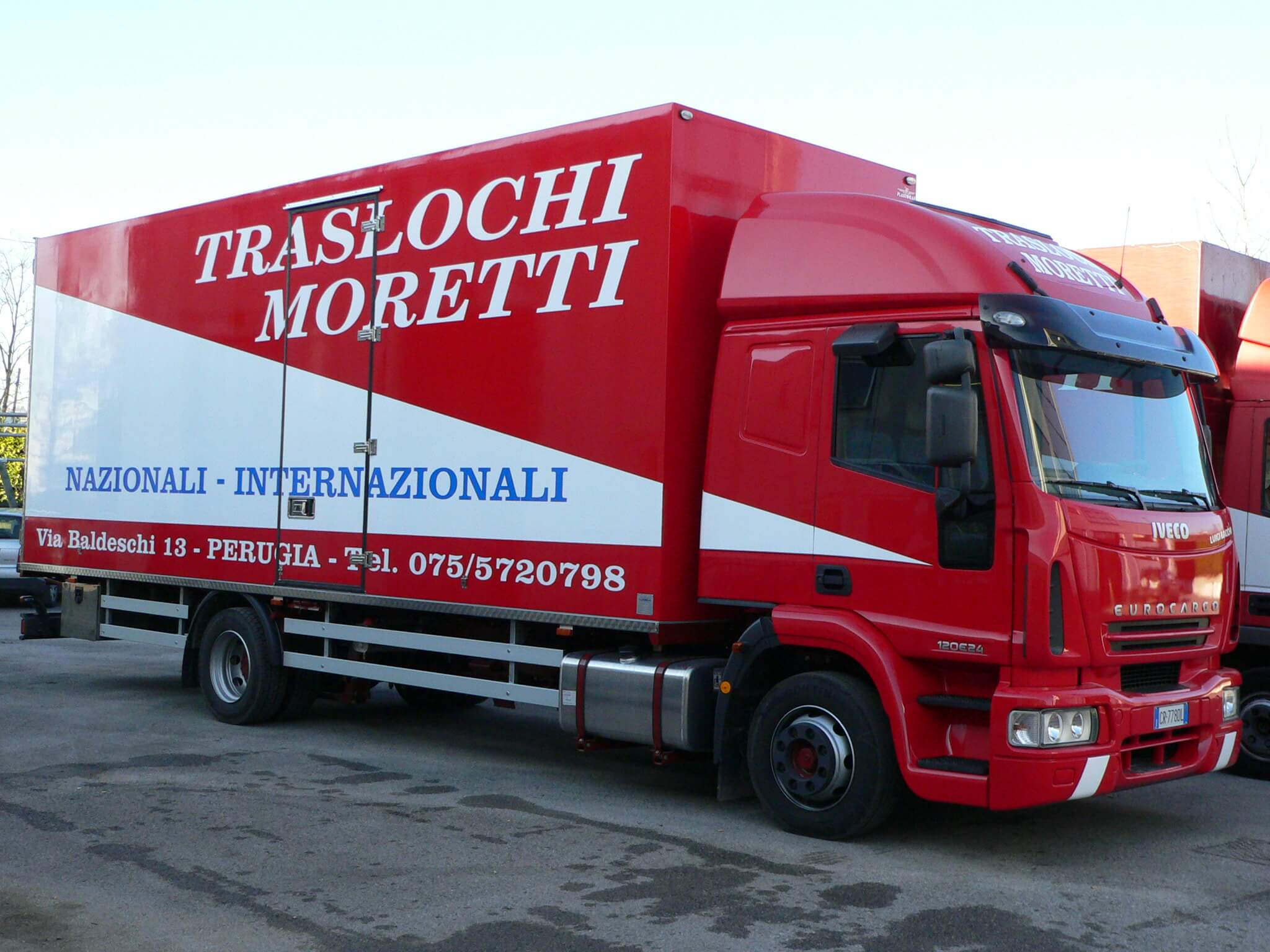 Camion per traslochi Tralochi Moretti rosso e bianco. Sulla fiancata è scritto