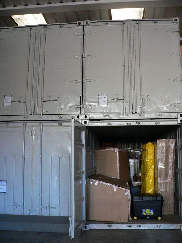Container impilati, uno aperto che rivela scatole e oggetti imballati.