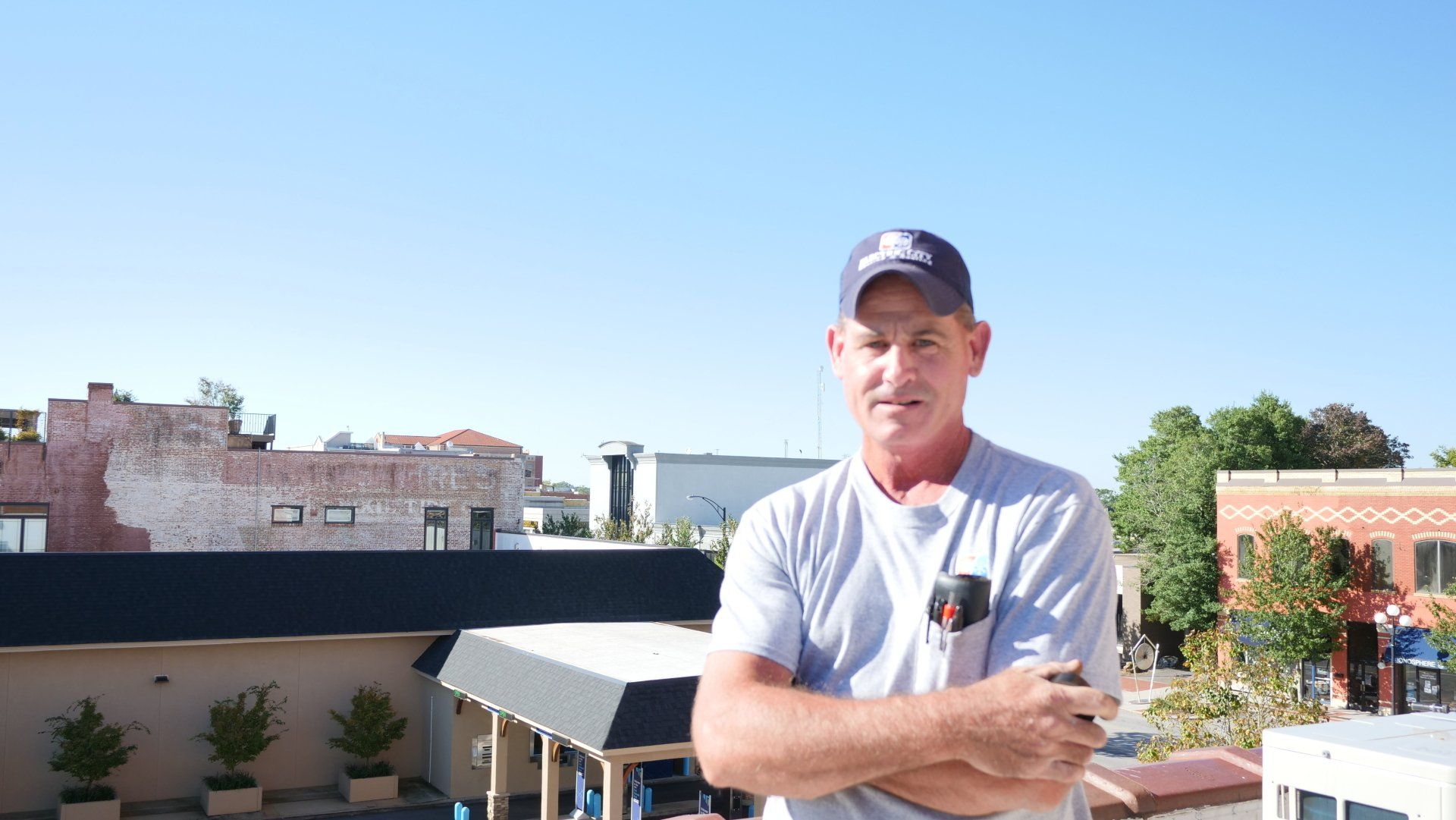 A man with his arms crossed is standing in front of a building