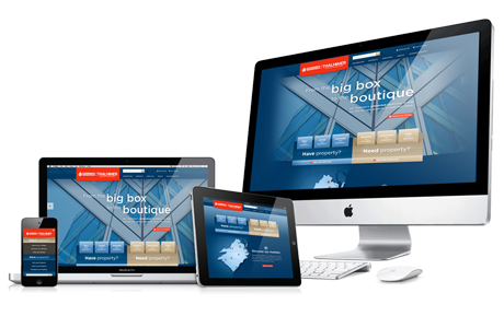 A computer monitor , laptop , tablet and phone are displaying a website for a big box boutique.