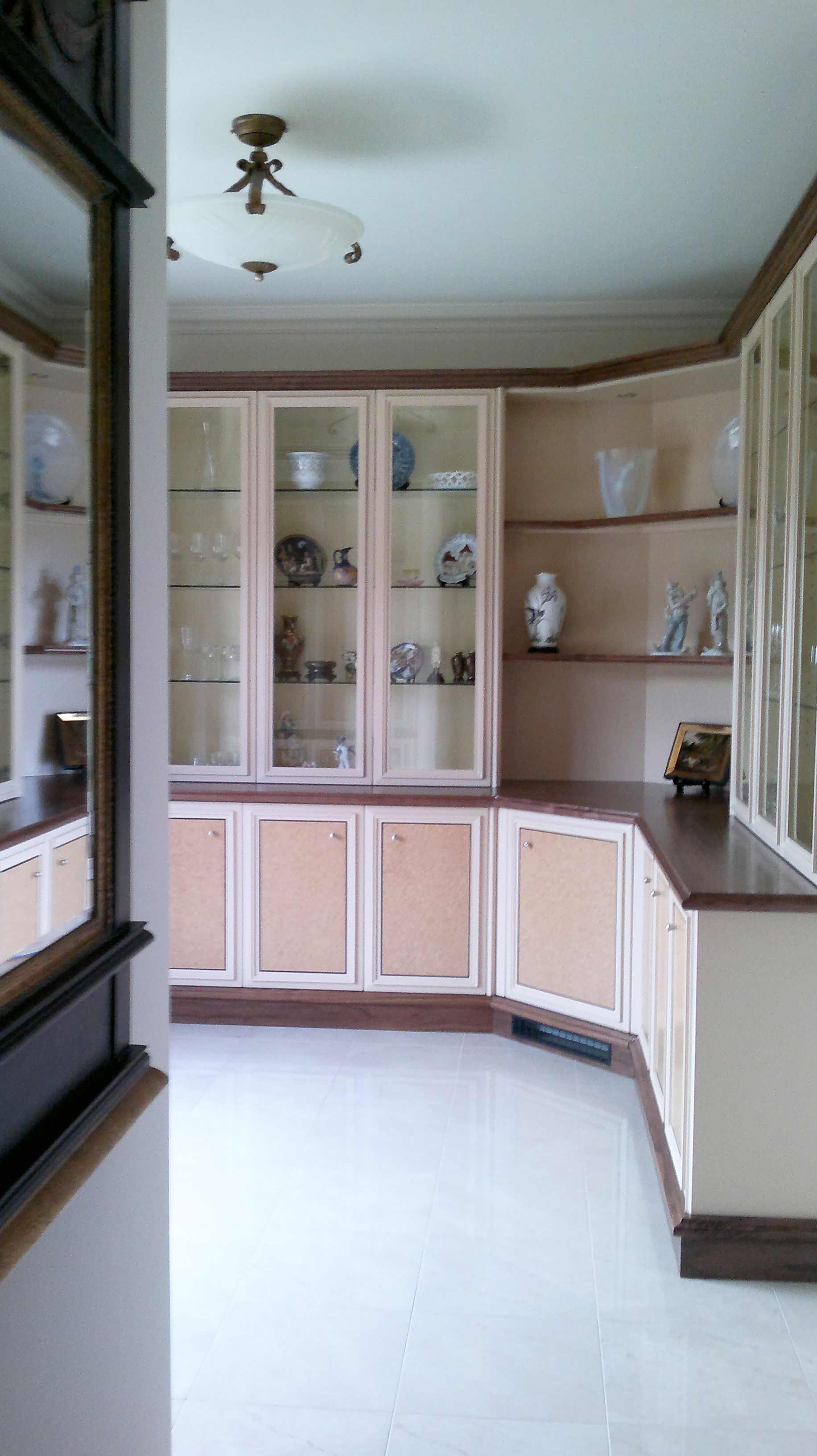 Built-in cream-colored cabinetry in a room with white tile floors and a mirror on the left.