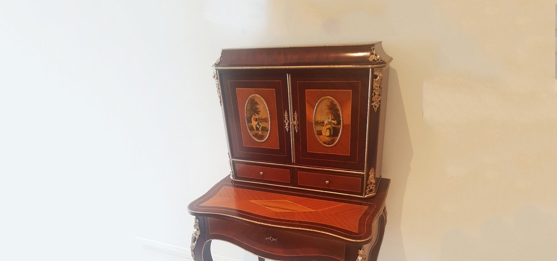 Dark wooden desk with a cabinet, featuring gold accents, against a light wall.