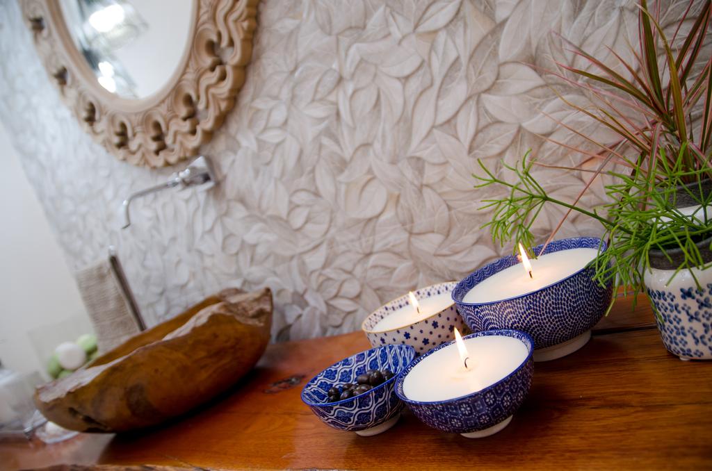 Três velas estão sobre uma mesa de madeira em um banheiro.