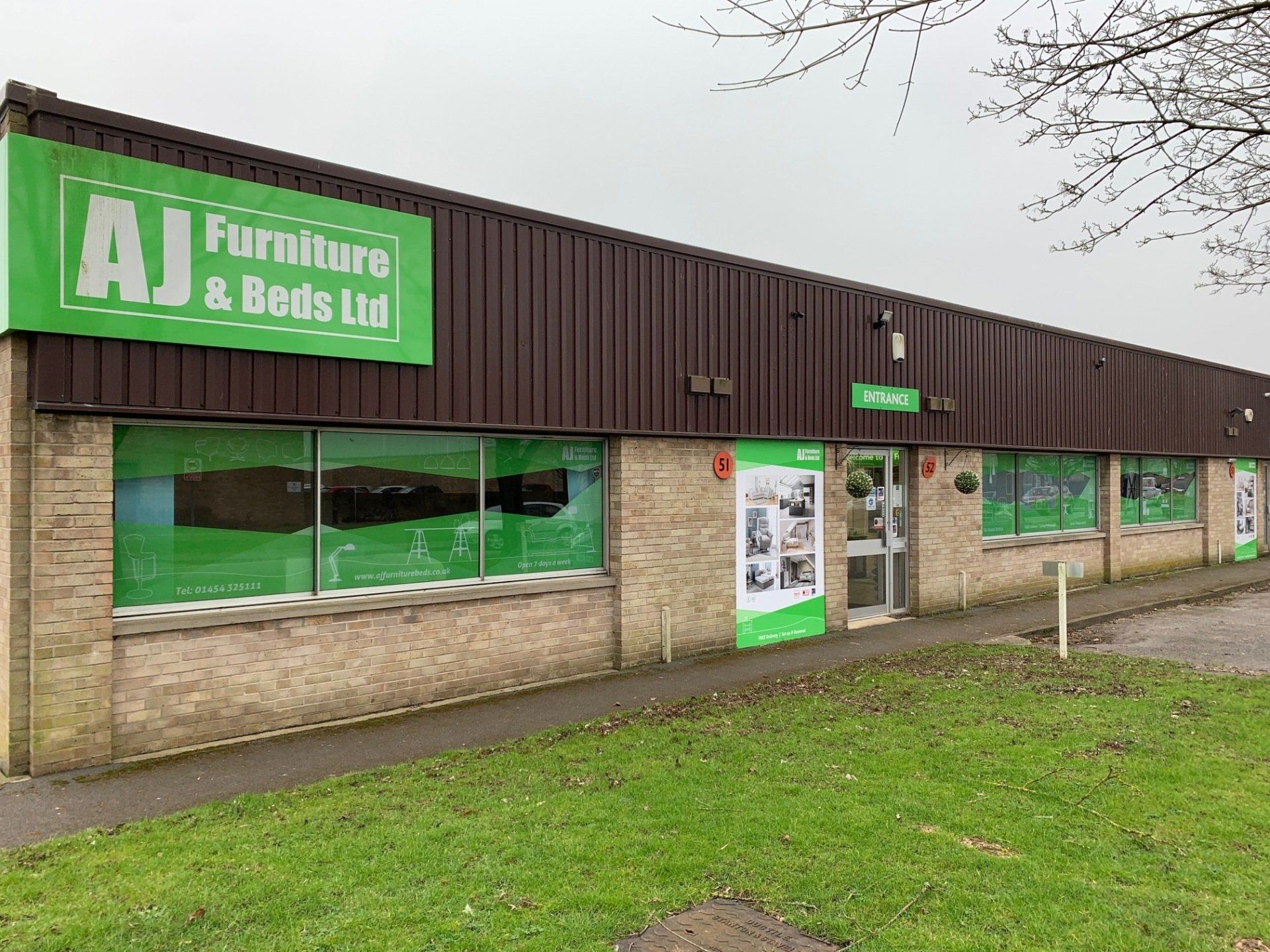 A large brick building with a green sign that says aj furniture and beds ltd.