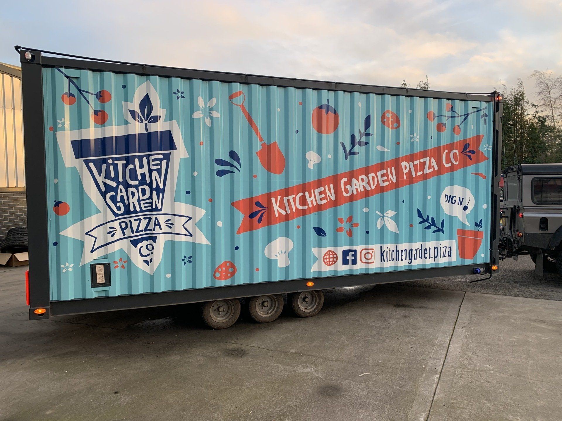 A kitchen garden pizza truck is parked in a parking lot.